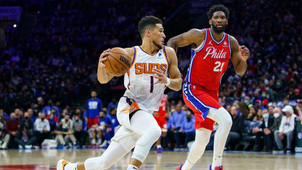 Phoenix Suns' Devin Booker, left, drives to the basket against Philadelphia 76ers' Joel Embiid, right, during the second half of an NBA basketball game, Tuesday, Feb. 8, 2022, in Philadelphia. The Suns won 114-109.